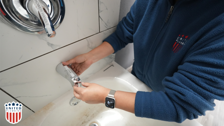 United Plumbing technician repairing a bathroom faucet spout near a shower handle above a sink.