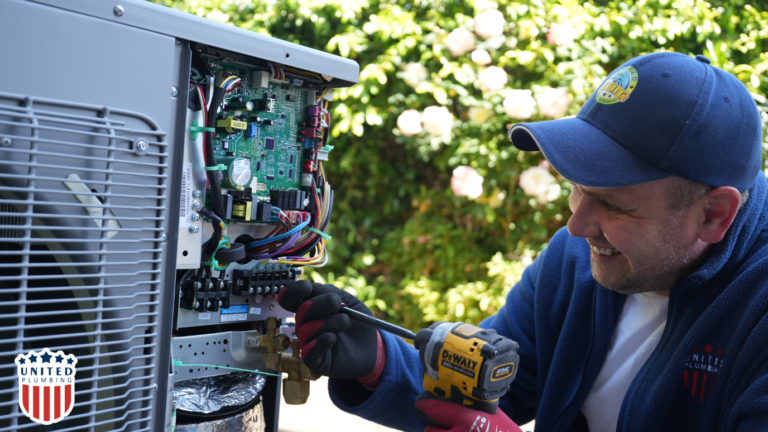 Technician from United Plumbing smiling while working on installing a subpanel and electrical system outdoors.