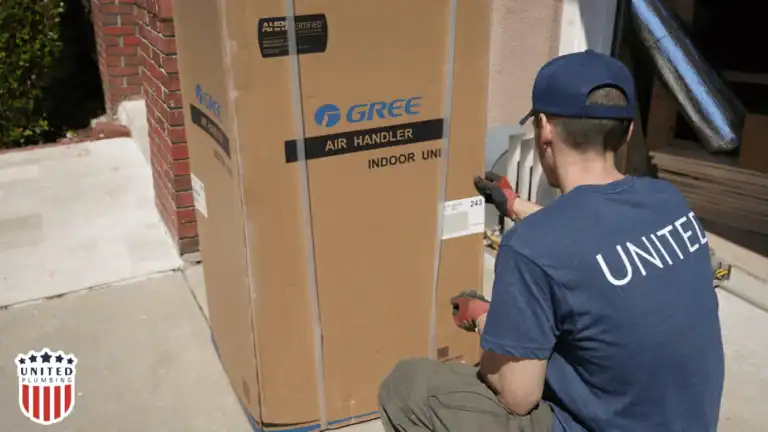 United Plumbing technician kneels beside a Gree air handler unit outside a home, checking shipment details before HVAC system installation.

