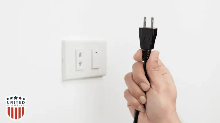 Person unplugging an electrical cord from a wall outlet to reduce standby power and improve safety