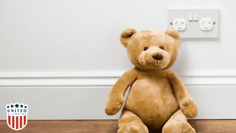 Child’s teddy bear placed near a wall outlet with safety covers, emphasizing childproof electrical safety at home.