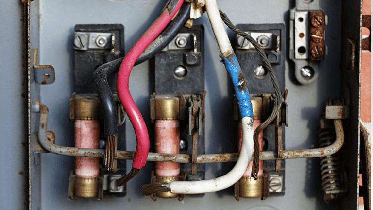 Close-up of an old electrical panel with damaged wires, showing a potential short circuit that can cause breakers to trip.